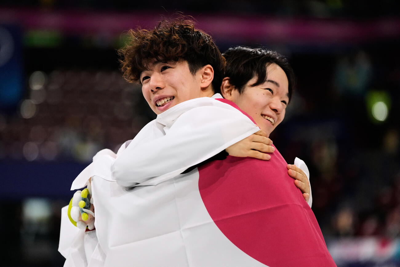 抱き合う銀メダルの鍵山（奥）と銅メダルの佐藤（AP）