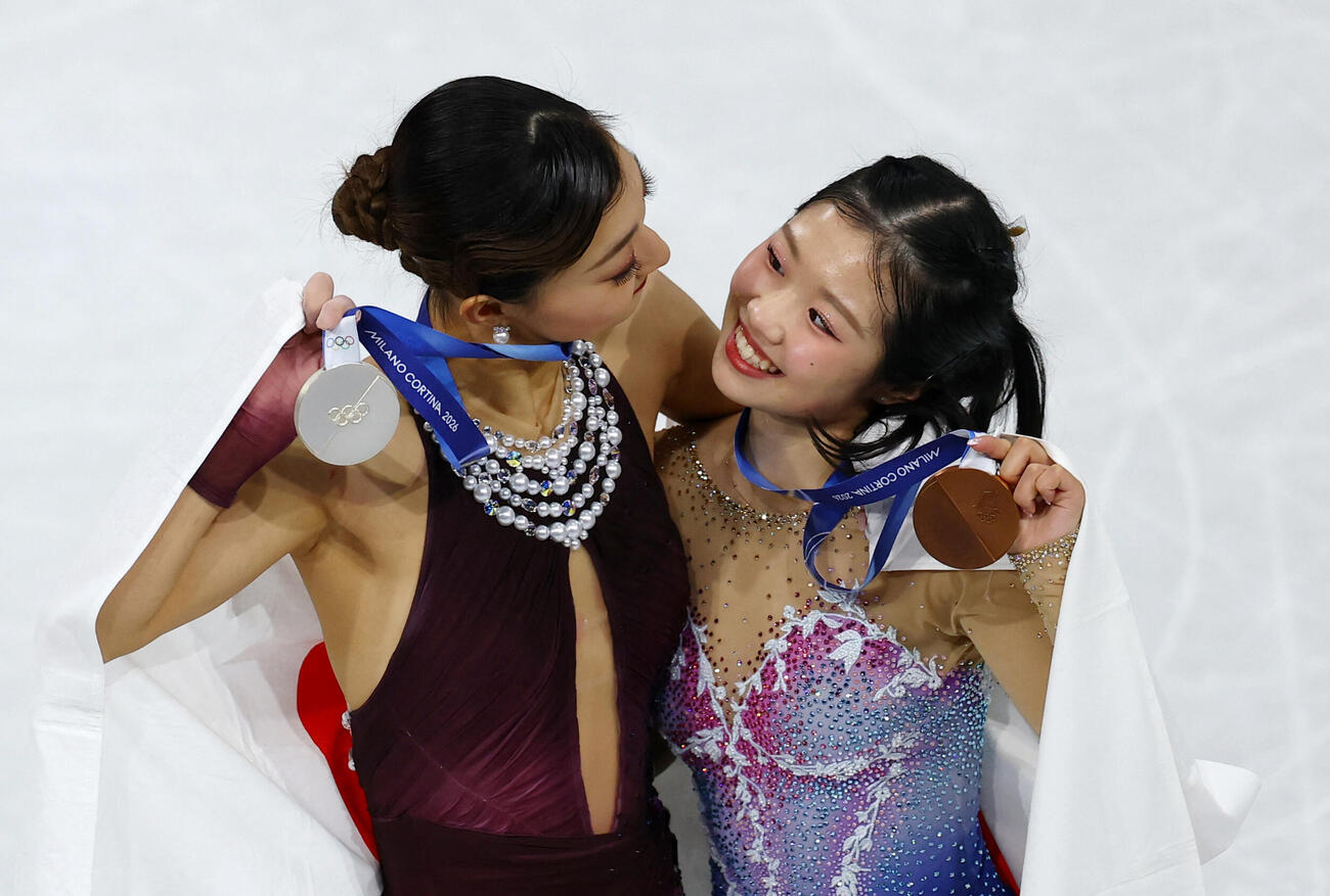 メダルを掲げて見つめ合う坂本花織（左）と中井亜美（ロイター）