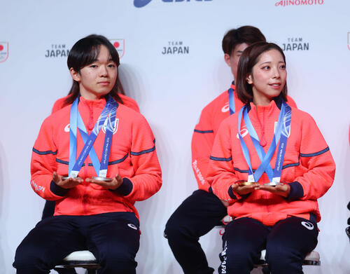 帰国時記者会見でメダルを重そうに手にもつ鍵山(左)と三浦(撮影・増田悦実)