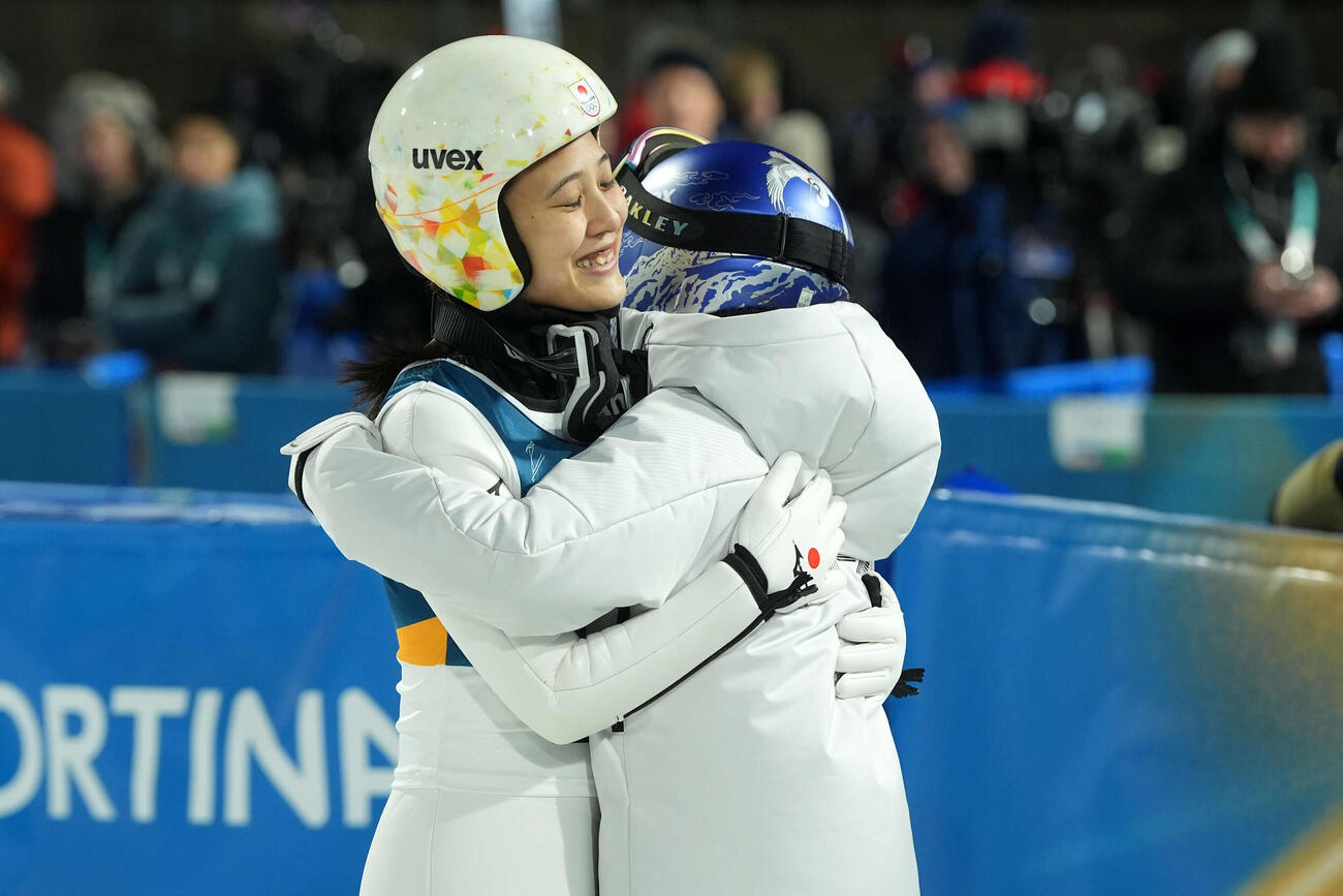 女子個人ラージヒル　飛躍を終え、高梨（右）とハグする丸山（撮影・パオロ　ヌッチ）