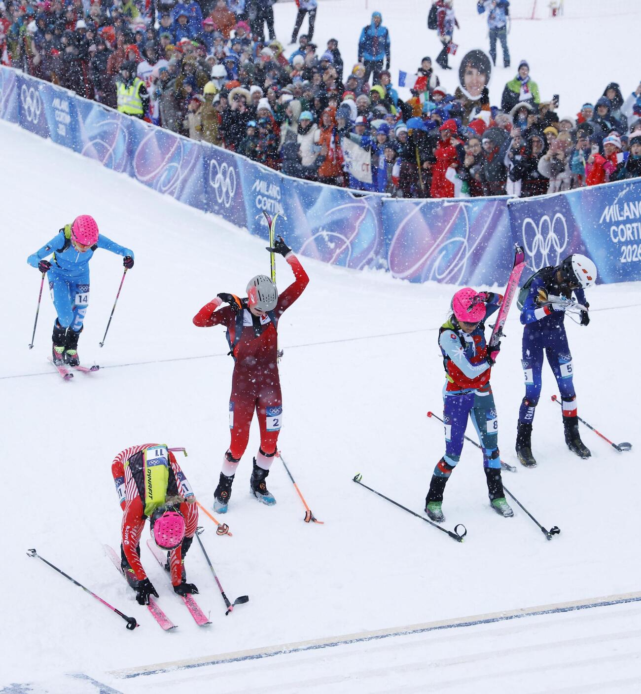 山岳スキー女子スプリント予選で、スキー板を外して背負う選手たち＝19日、イタリア・ボルミオ（共同）
