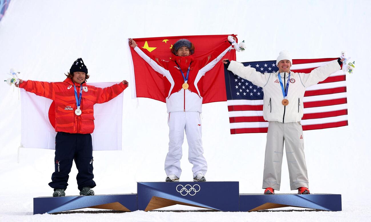 金メダリストの中国の蘇翊鳴が、銀メダリストの日本の長谷川帝勝、銅メダリストのアメリカのジェイク・カンターとともに表彰台で喜びを分かち合う（ロイター）