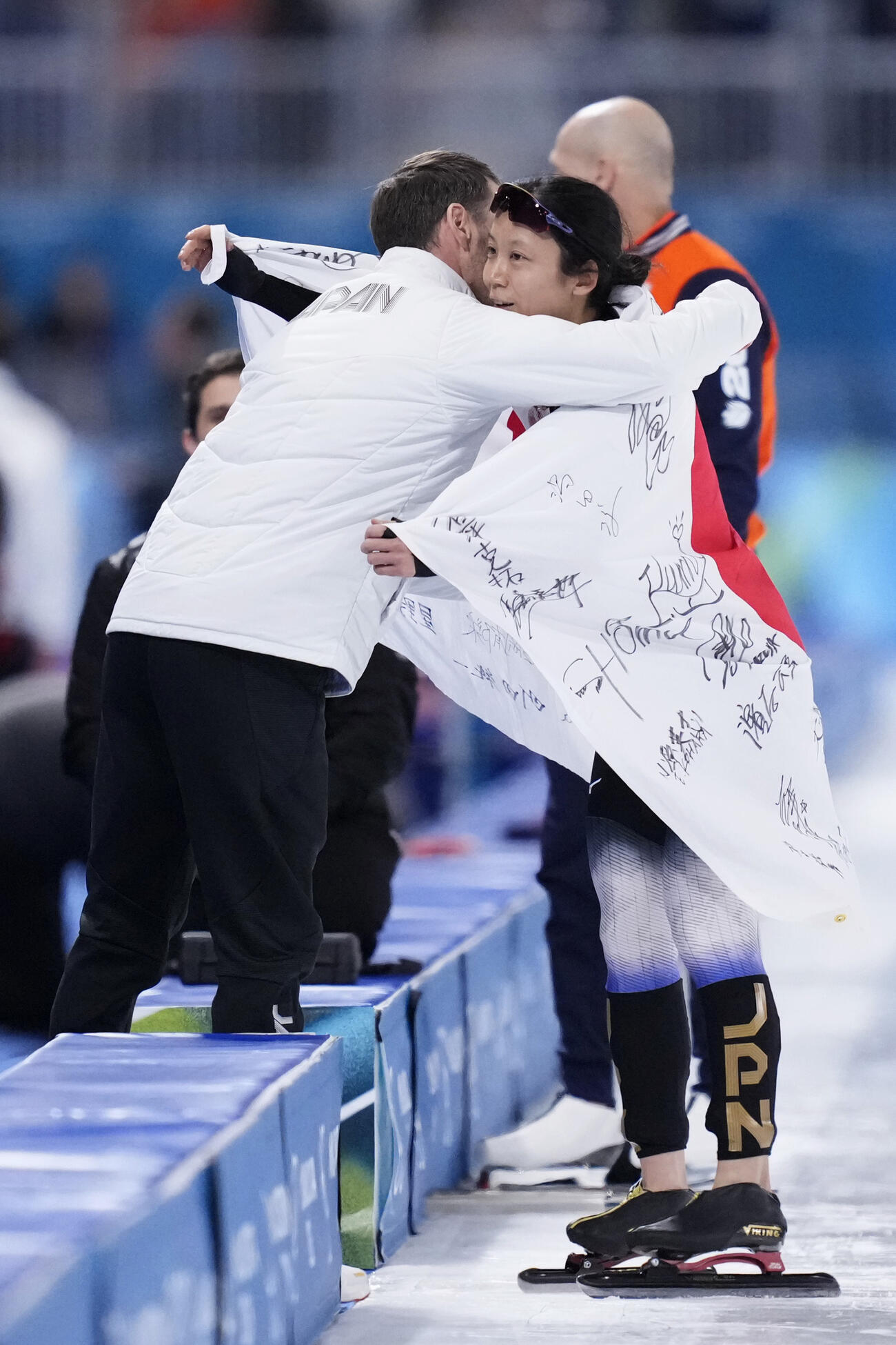 女子1000メートルで銅メダルを獲得しヨハン・デビット・コーチ（左）と抱き合う高木美帆＝ミラノ（共同）