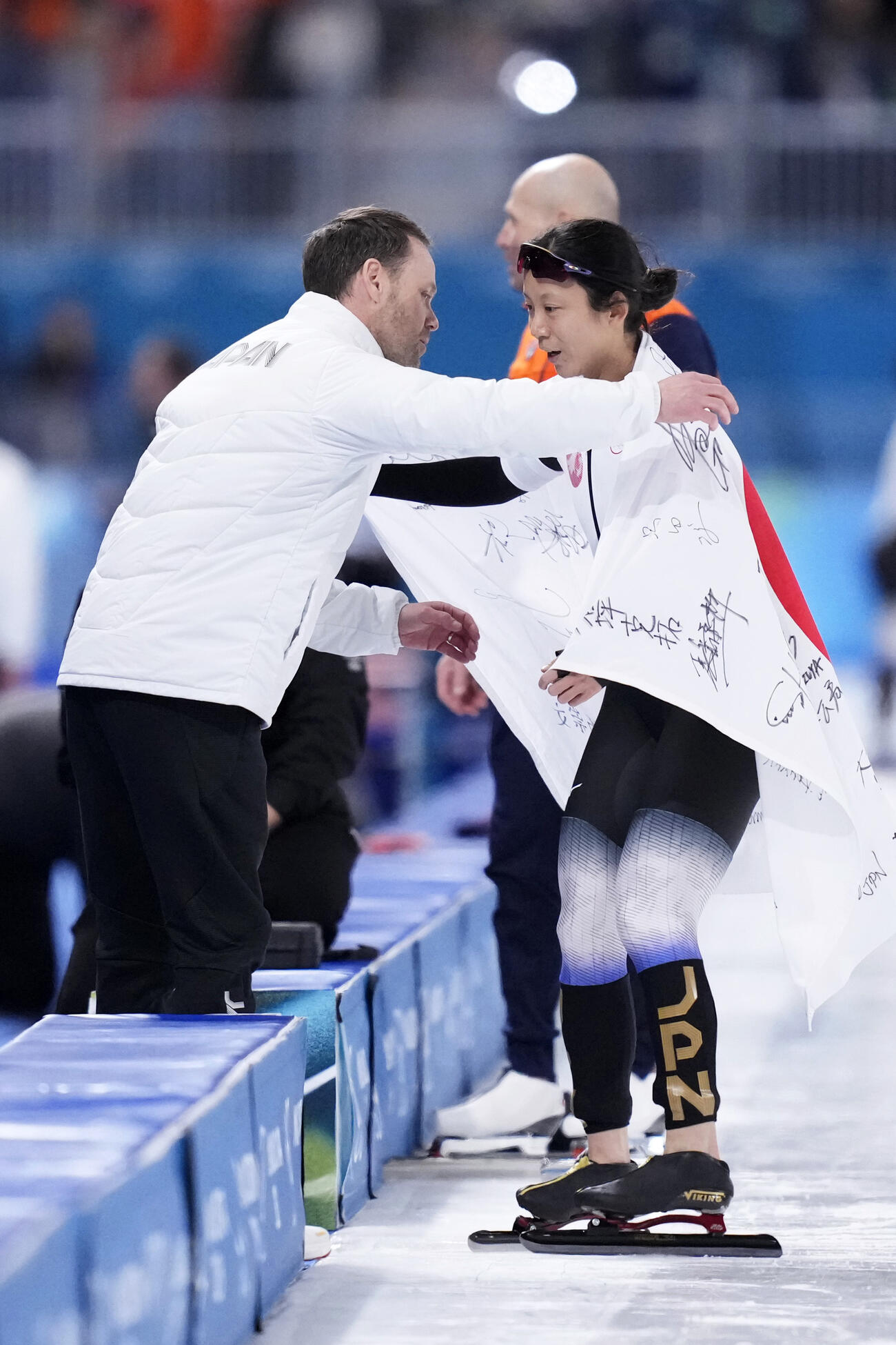 女子1000メートルで銅メダルを獲得しヨハン・デビット・コーチ（左）と抱き合う高木美帆＝ミラノ（共同）