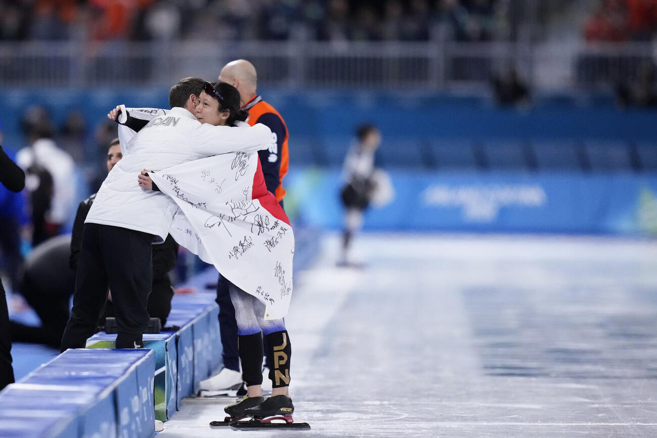女子1000メートルで銅メダルを獲得しヨハン・デビット・コーチ（左）と抱き合う高木美帆＝ミラノ（共同）