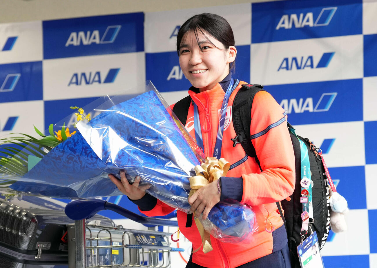 帰国し花束を手に笑顔を見せる女子スピードスケートの野明（撮影・小島史椰）