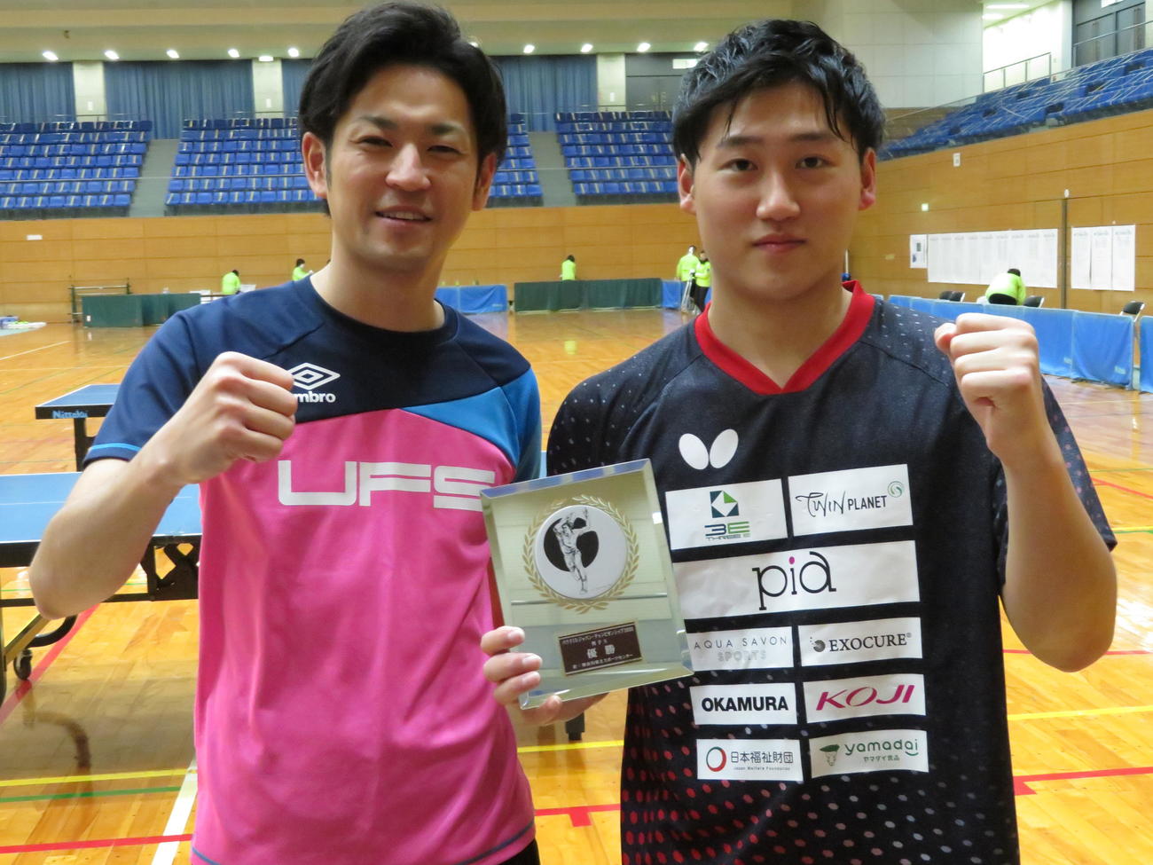 男子シングルスで2連覇を達成した浅野俊（右）は佐々木信也コーチとガッポーズ（撮影・小堀泰男）