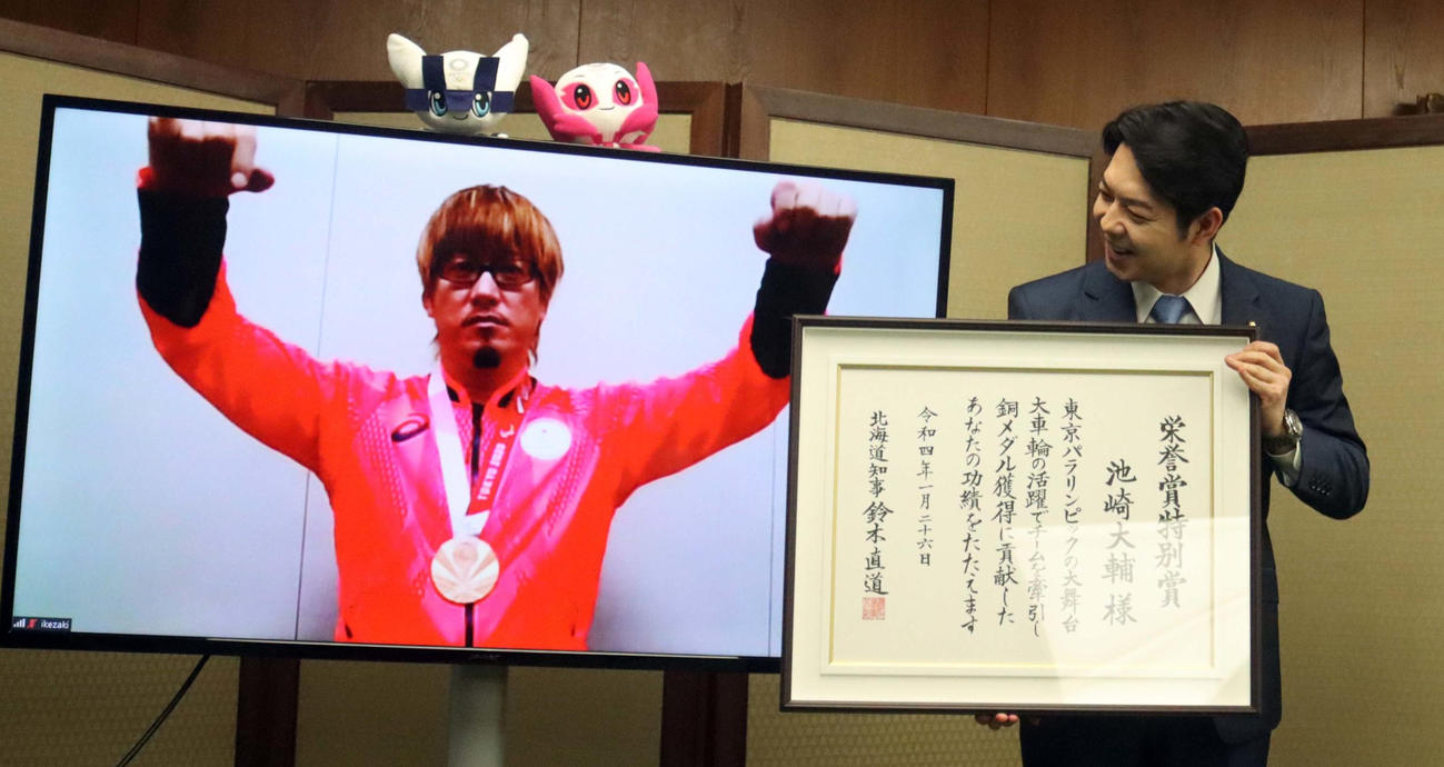 リモートでの表彰式に参加し両手を挙げ喜ぶ池崎（左）。右は鈴木知事（撮影・永野高輔）