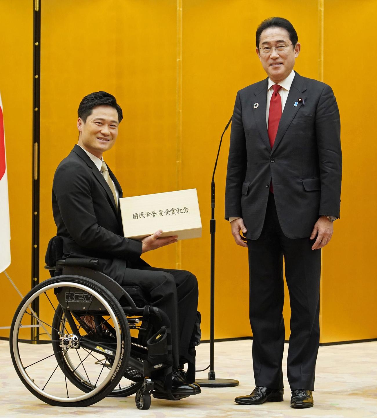 国民栄誉賞表彰式で、岸田首相（右）から記念品を受け取る元車いすテニス男子の国枝慎吾さん（共同）
