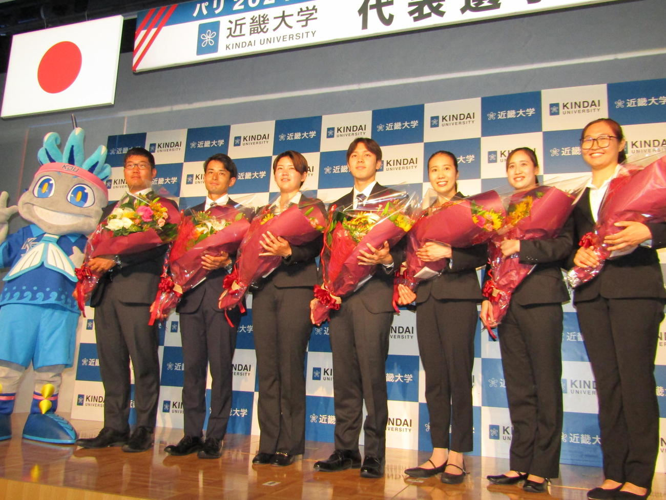 近大の五輪壮行会に出席した左から、マスコット人形、アーチェリーの古川高晴、中西絢哉、野田紗月、パラリンピック水泳の南井瑛翔、アーティスティックスイミングの安永真白、木島萌香、柔道女子モンゴル代表オトゴンバヤル・フスレン