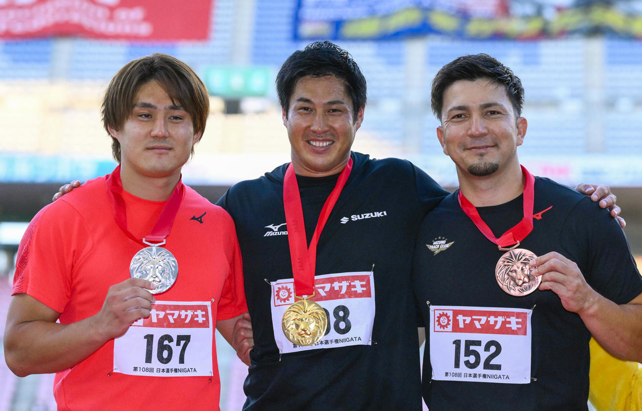 男子やり投げで優勝し表彰式で笑顔の新井涼平。左は2位の崎山雄太、右は3位のディーン元気（共同）