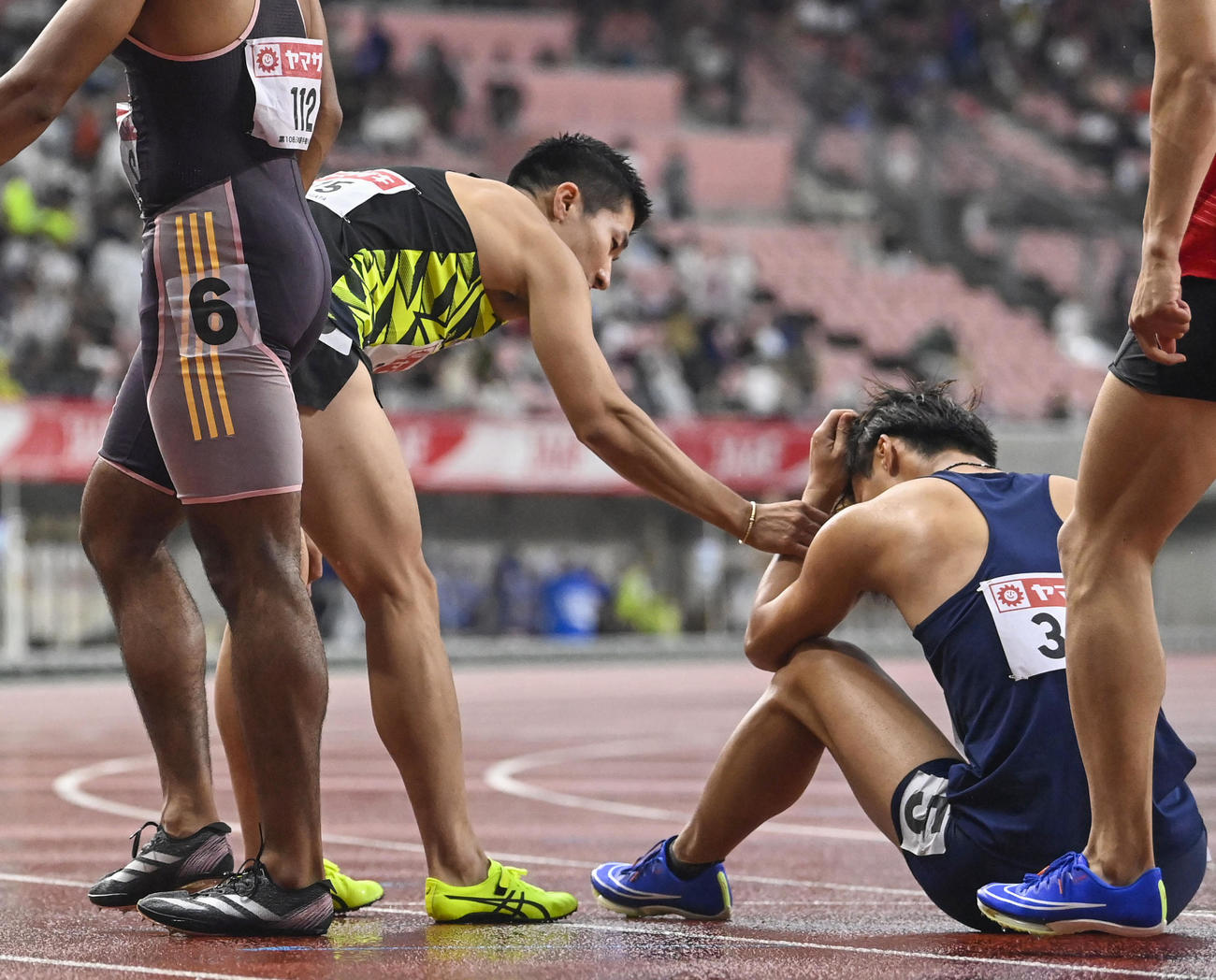男子100メートル決勝を終え、座り込む柳田大輝に声をかける桐生祥秀（左）（共同）