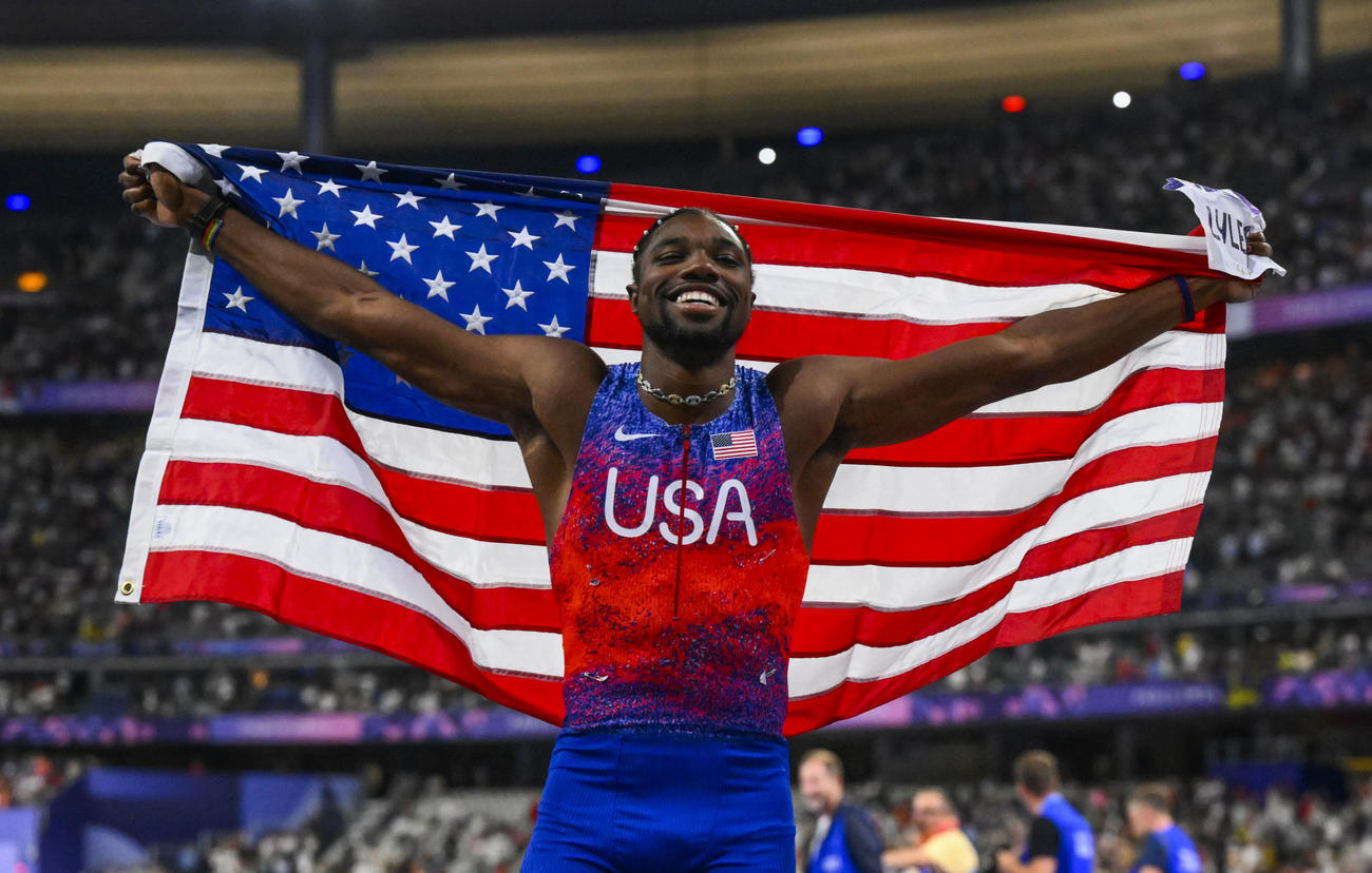 男子100メートルで優勝し、国旗を掲げる米国のライルズ（共同）