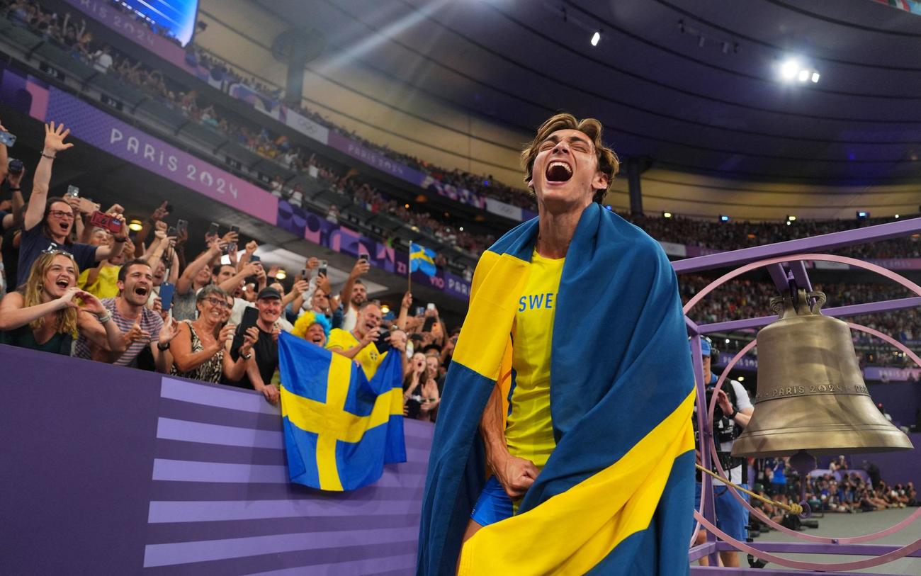 陸上男子棒高跳び決勝、世界新となる6メートル25センチを成功させた、スウェーデンのデュプランティスは国旗を身にまとい、笑顔を見せる（ロイター）