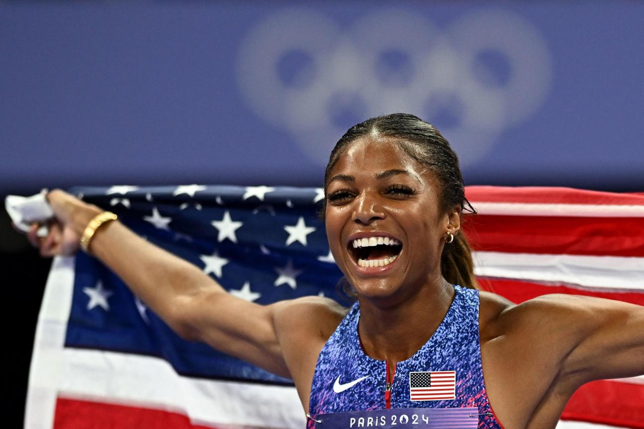 女子200メートルで優勝し、国旗を掲げる米国のトーマス（ロイター）