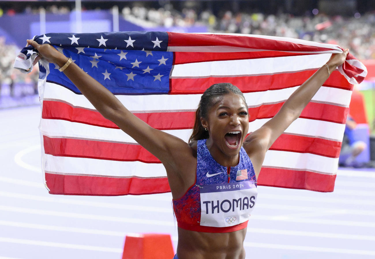 女子200メートルで優勝し、国旗を掲げる米国のトーマス（共同）