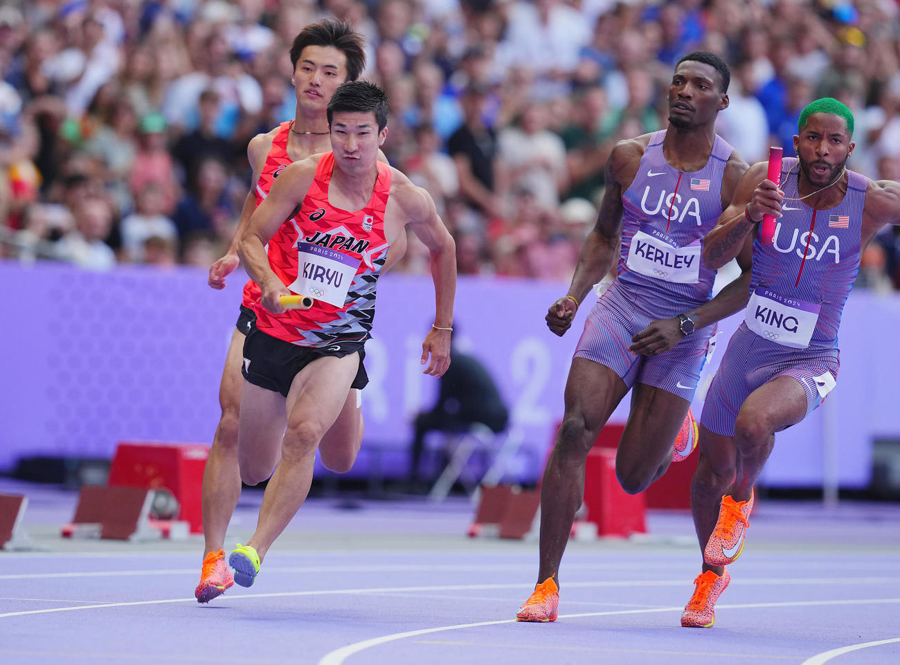 陸上男子400メートルリレー予選、2走柳田（左奥）からバトンを受け取り走り出す3走桐生（撮影・垰建太）