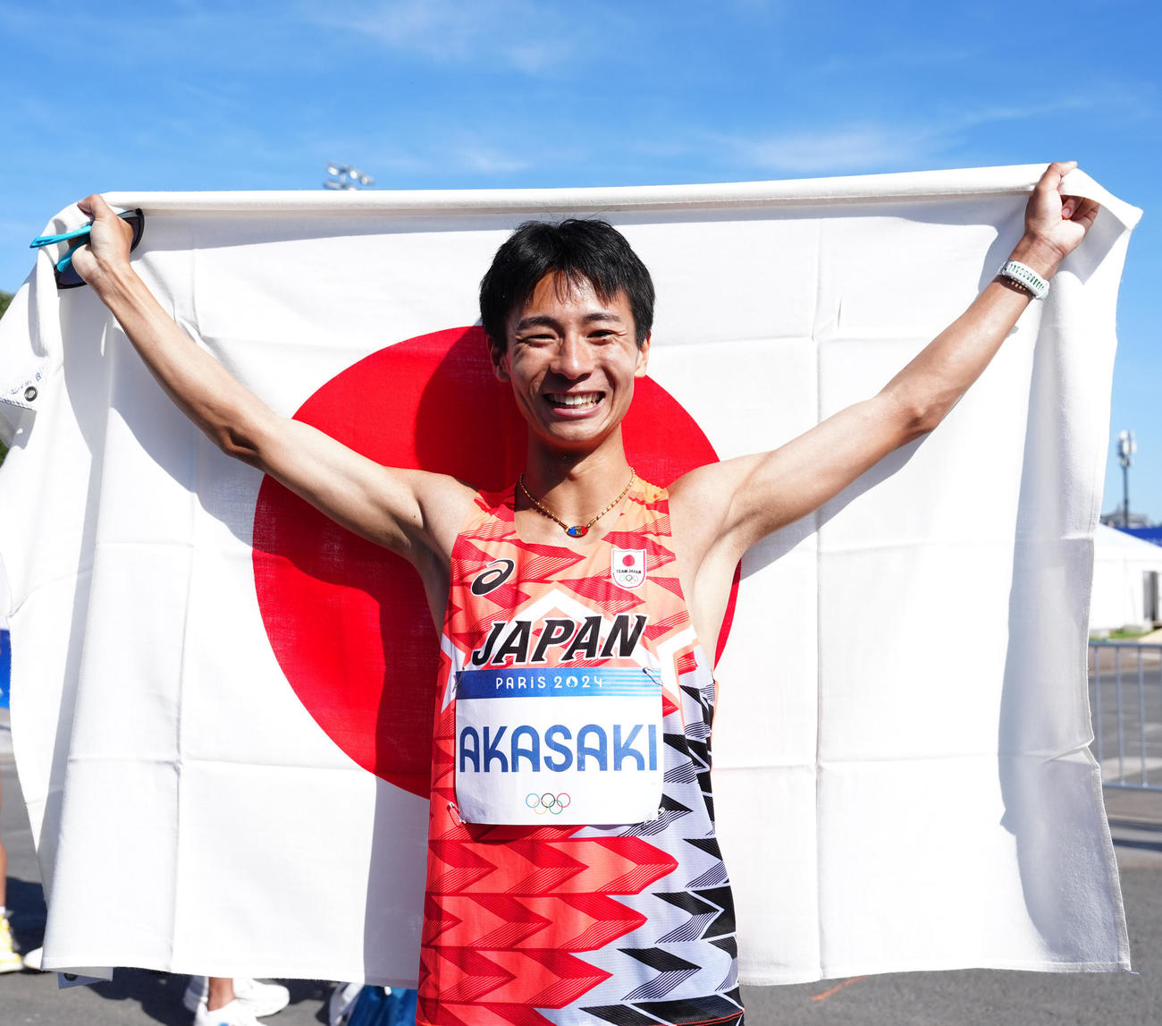 男子マラソンで6位入賞となり、日の丸を掲げ笑顔を見せる赤崎（撮影・江口和貴）