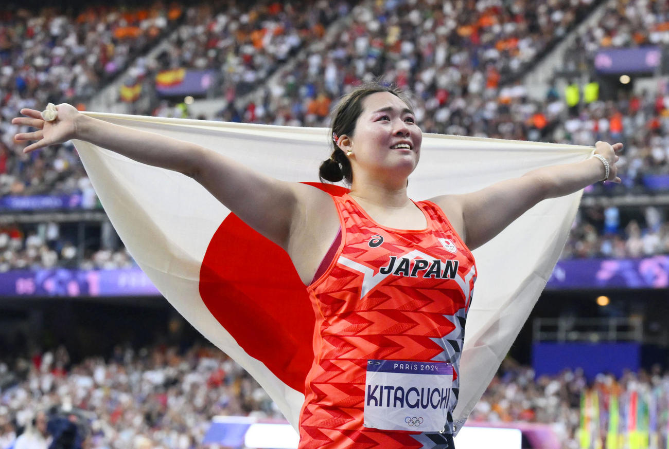 女子やり投げで金メダルを獲得し、日の丸を掲げる北口榛花（共同）
