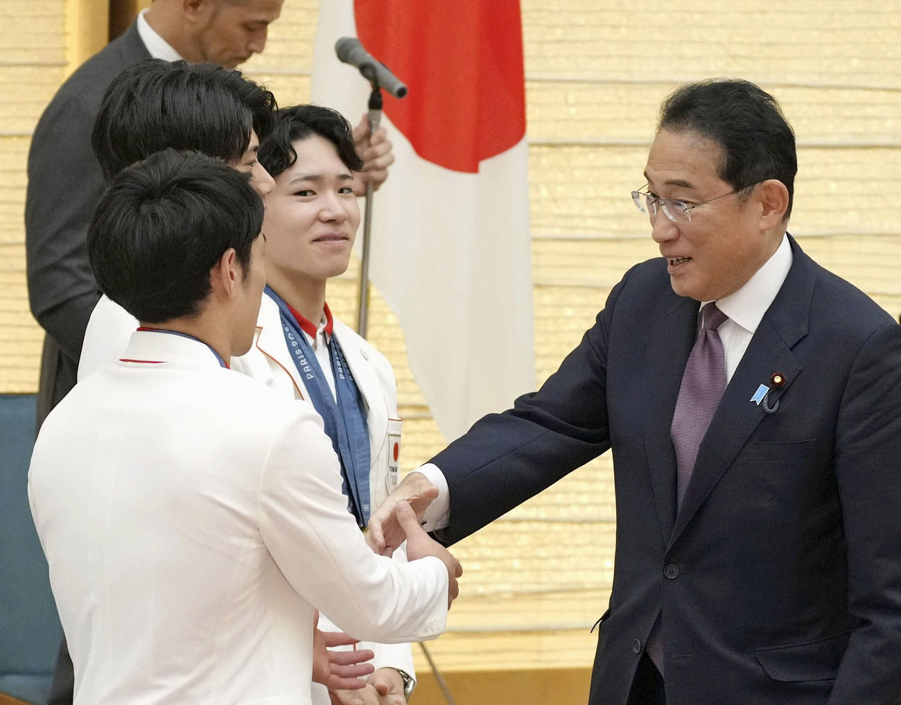 パリ五輪の日本選手団メダリストらと握手を交わす岸田首相（右）。奥は体操男子の岡慎之助選手（共同）