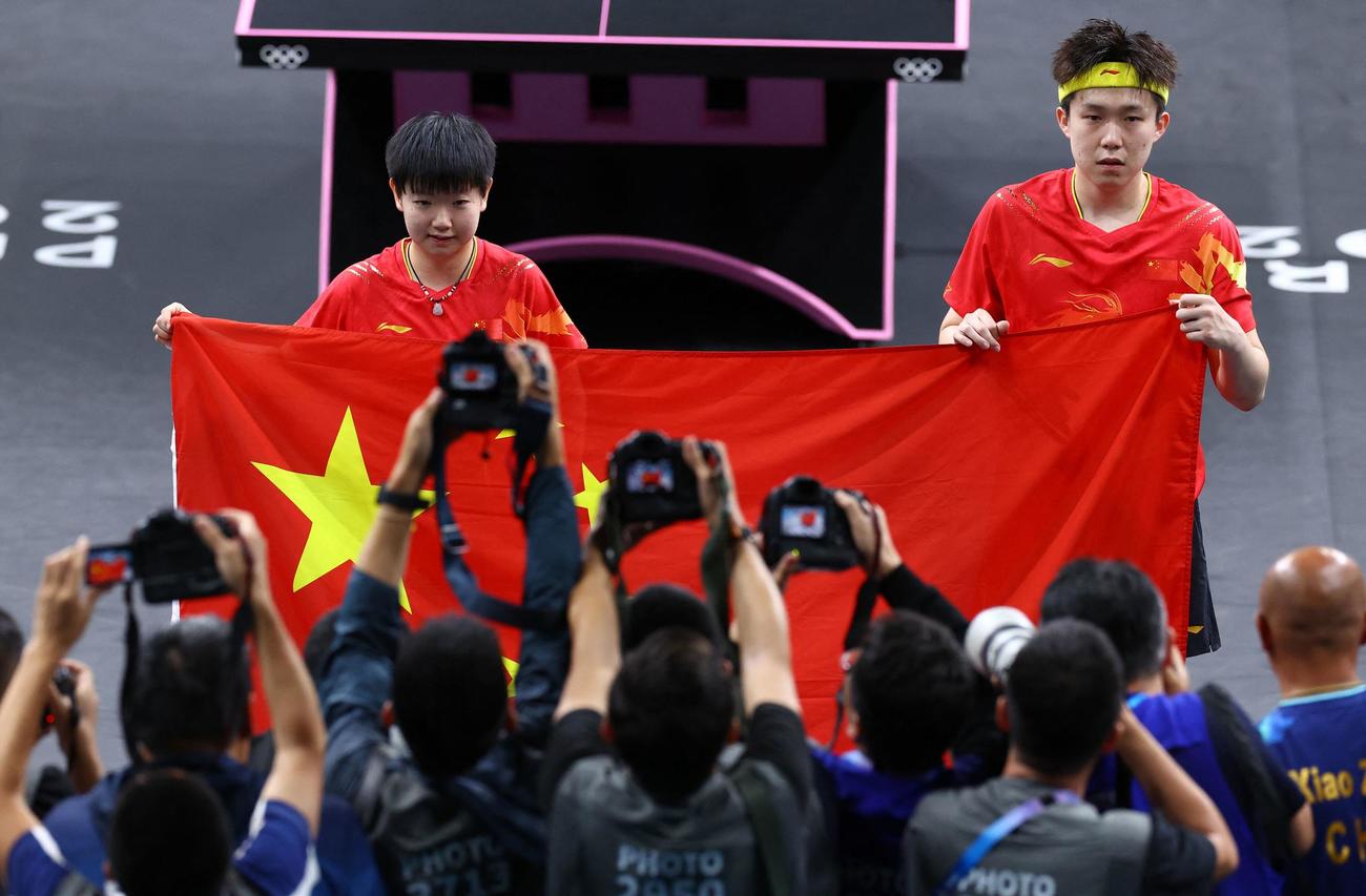 パリ五輪卓球混合ダブルス　金メダルを獲得し、撮影に応じる中国ペアの孫穎莎（左）と王楚欽（ロイター）