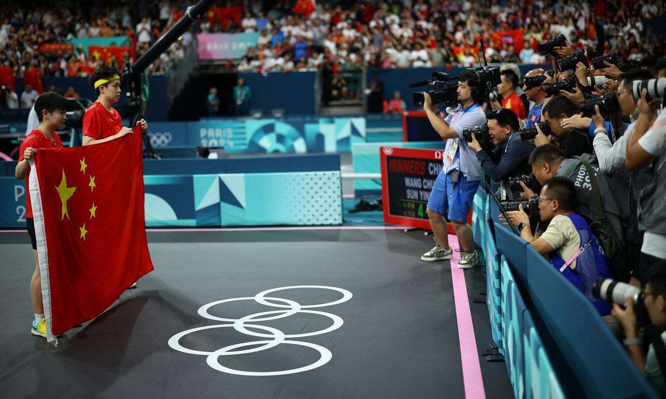 パリ五輪卓球混合ダブルス　金メダルを獲得し、撮影に応じる中国ペアの孫穎莎（左）と王楚欽（ロイター）