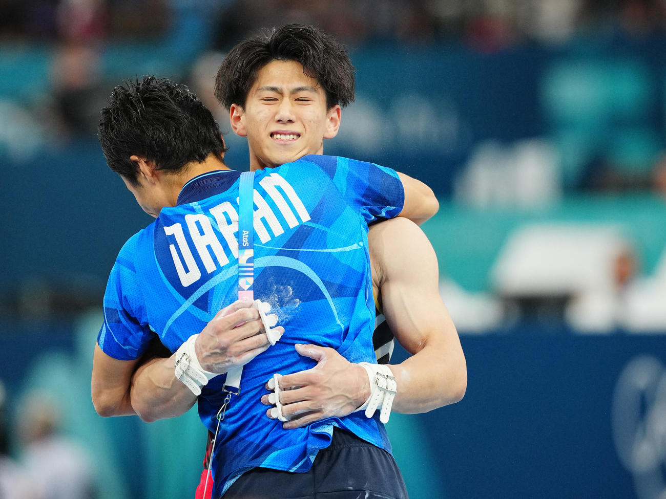 体操男子団体決勝、鉄棒の着地を決めスタッフと抱き合う橋本（撮影・垰建太）