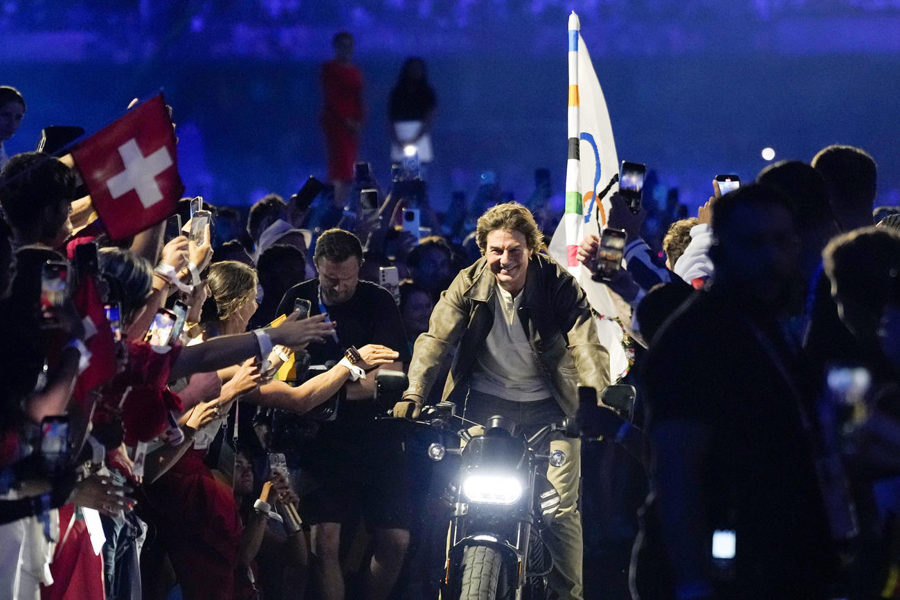 パリ五輪の閉会式で、バイクで疾走するトム・クルーズさん（中央）（AP＝共同）