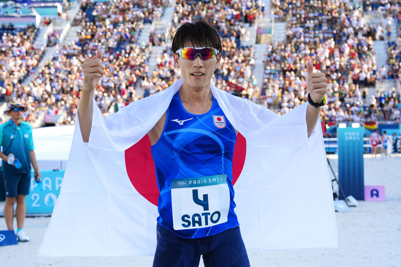 近代五種男子で銀メダルを獲得し、日の丸を背に喜ぶ佐藤大宗＝パリ郊外（共同）