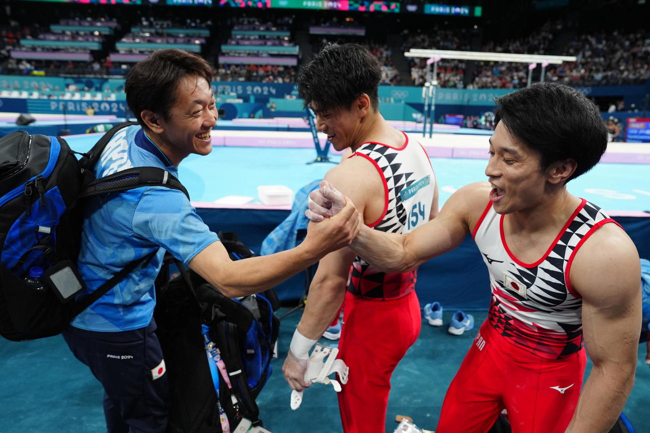 体操男子予選で平行棒の演技を終え、握手を交わす谷川（右）。中央は橋本（撮影・江口和貴）