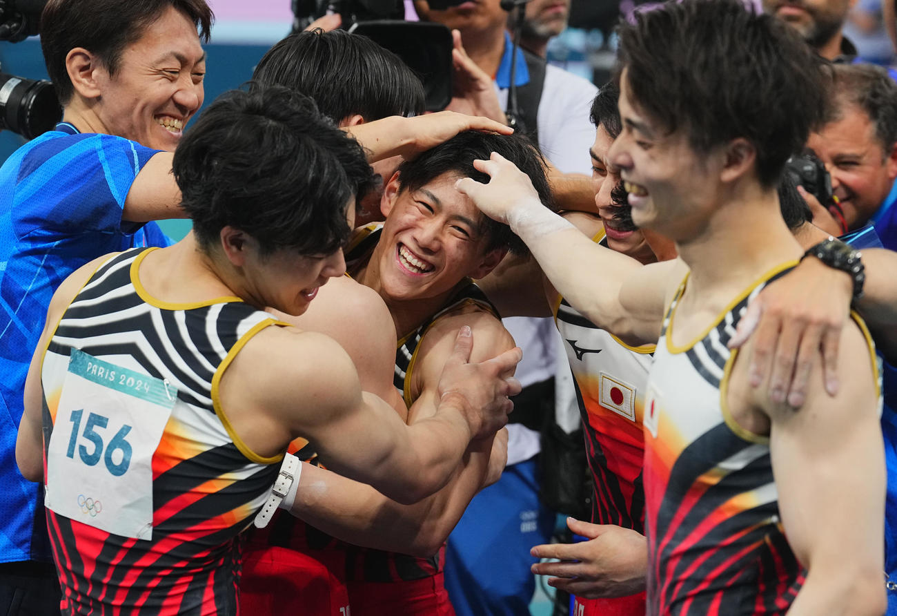 体操男子団体決勝、鉄棒の演技を終え仲間たちと歓喜の抱擁を交わす橋本（中央）（撮影・垰建太）