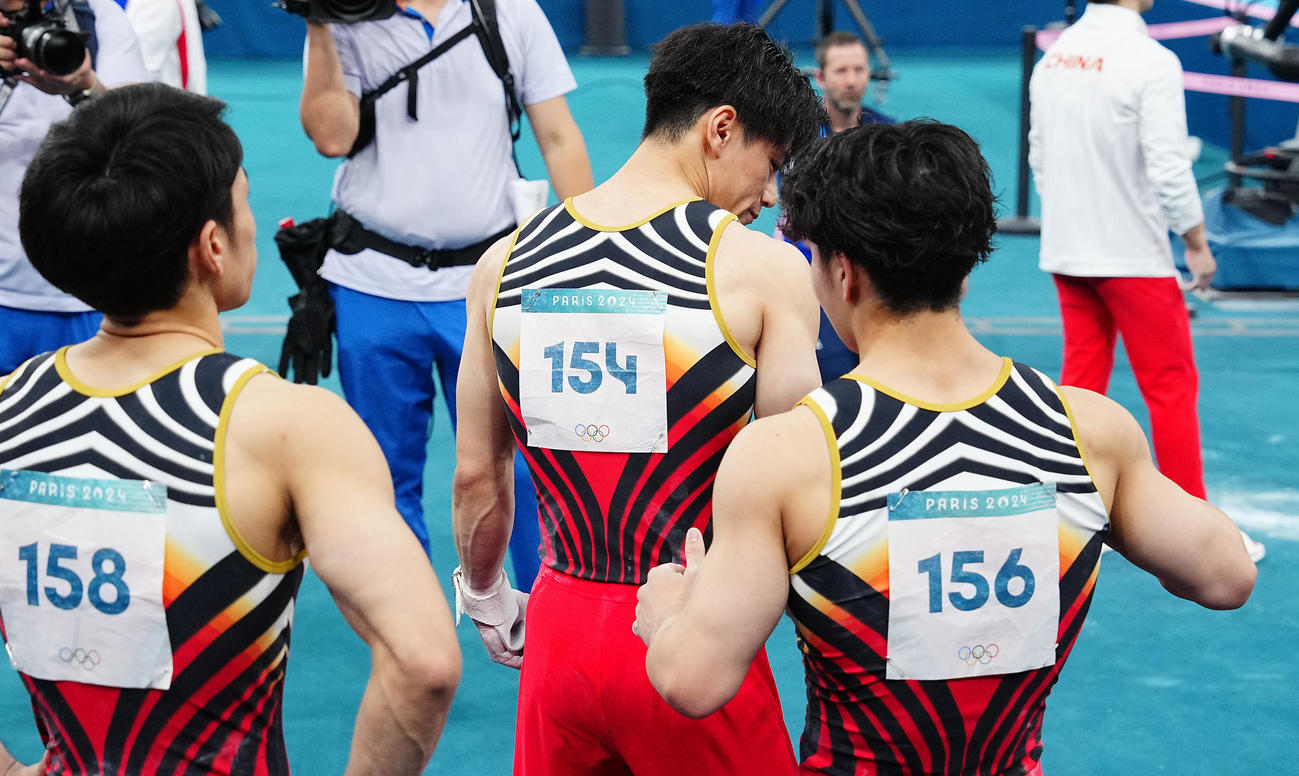 体操男子団体決勝、最終種目の鉄棒の演技を前に仲間たちに背中をたたくよう促す橋本（中央）（撮影・垰建太）