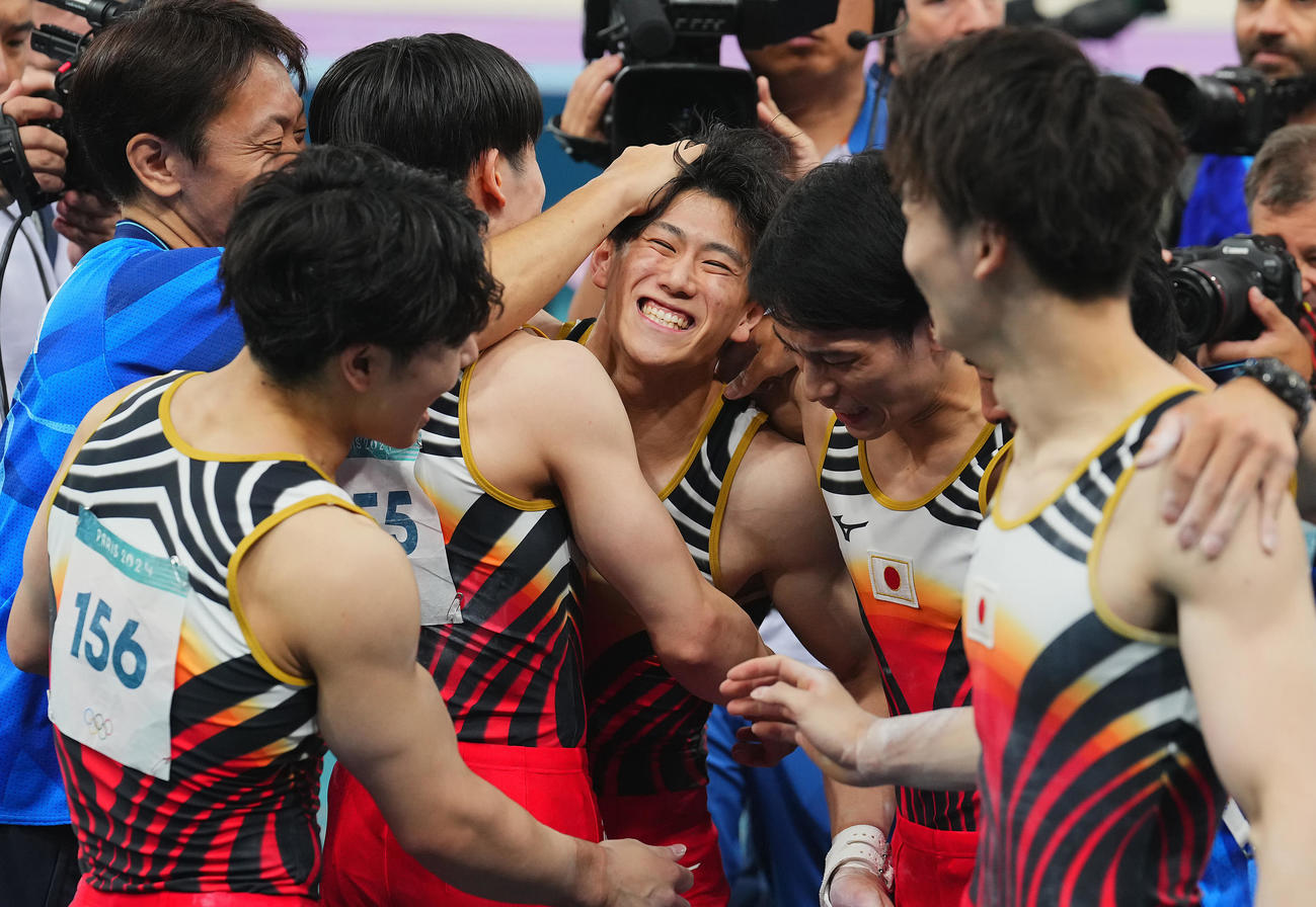 体操男子団体決勝、最終種目の鉄棒の演技を終え仲間たち歓喜の抱擁を交わす橋本（中央）（撮影・垰建太）