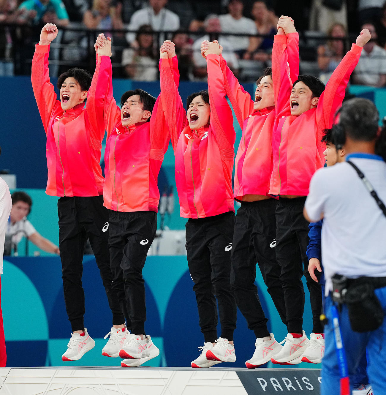 金メダルの日本の選手たちは手をつなぎジャンプで表彰台に上がる。左から橋本、萱、岡、杉野、谷川（撮影・垰建太）