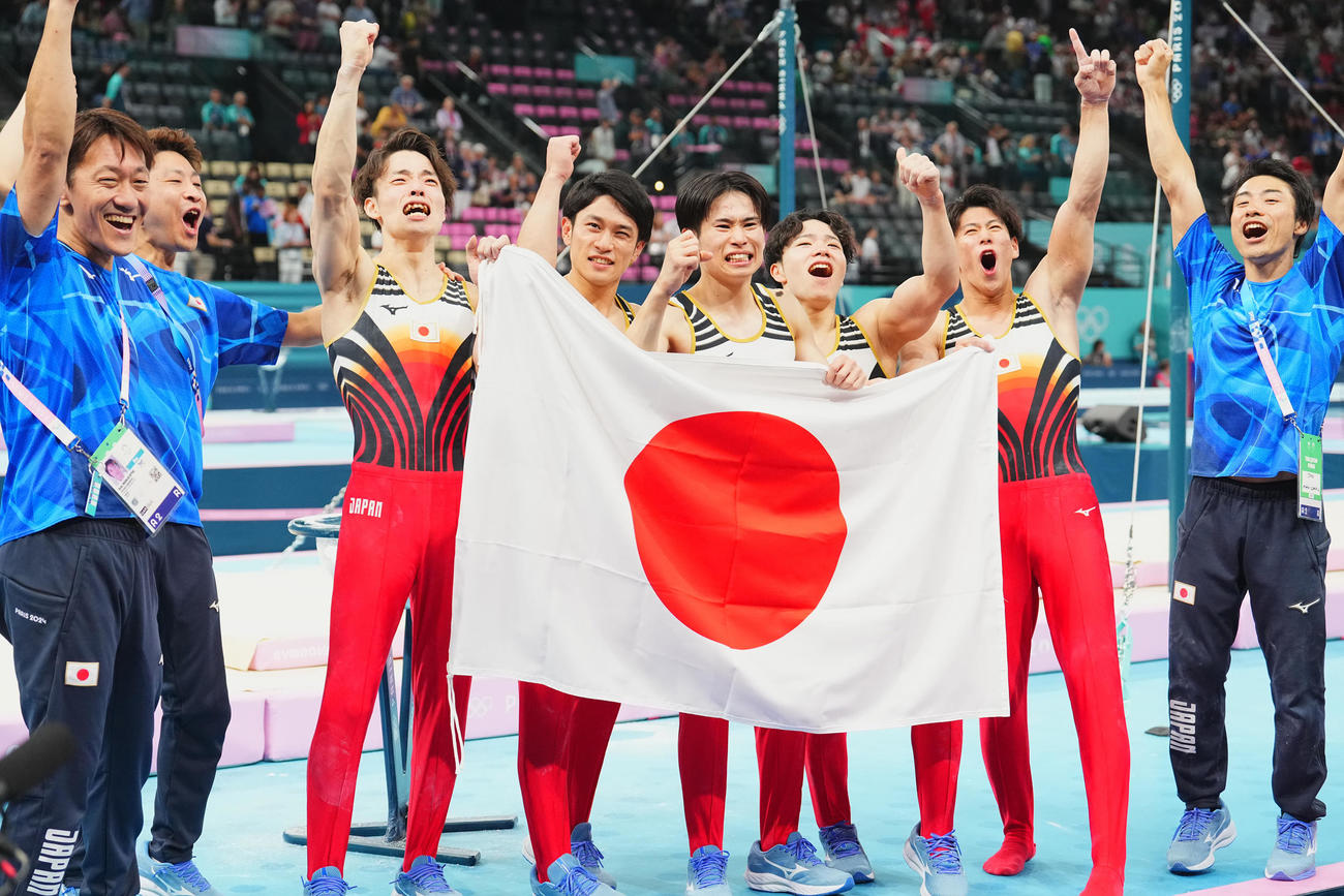 体操男子団体決勝、金メダルを決め日の丸を手に喜びを爆発させる日本の選手たち。左3人目から杉野、谷川、萱、岡、橋本（撮影・垰建太）