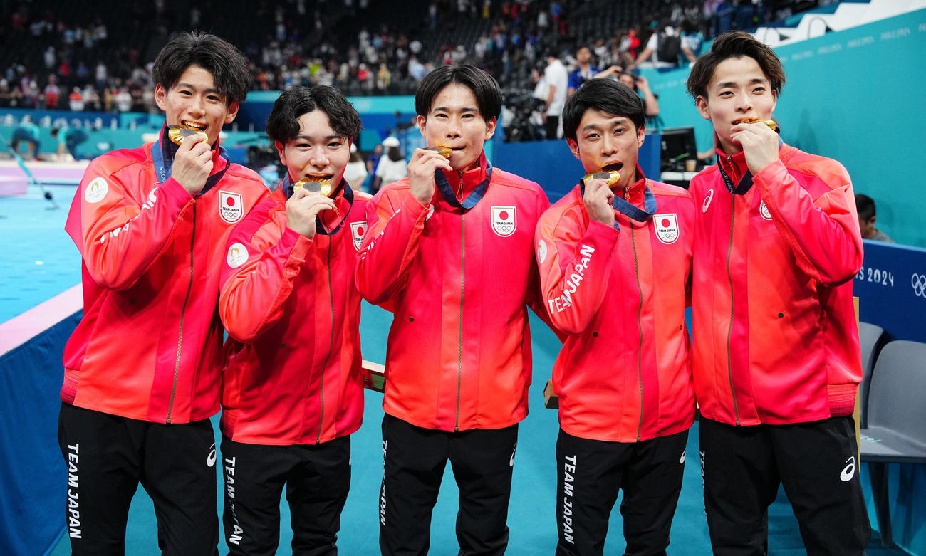 体操男子団体決勝、金メダルをかじる日本の選手たち。左から橋本、岡、萱、谷川、杉野（撮影・垰建太）