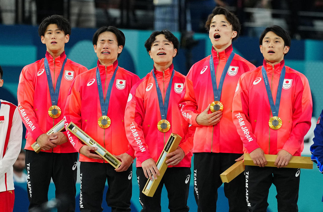 体操男子団体決勝、金メダルを首から下げ君が代斉唱する日本の選手たち。左から橋本、萱、岡、杉野、谷川（撮影・垰建太）