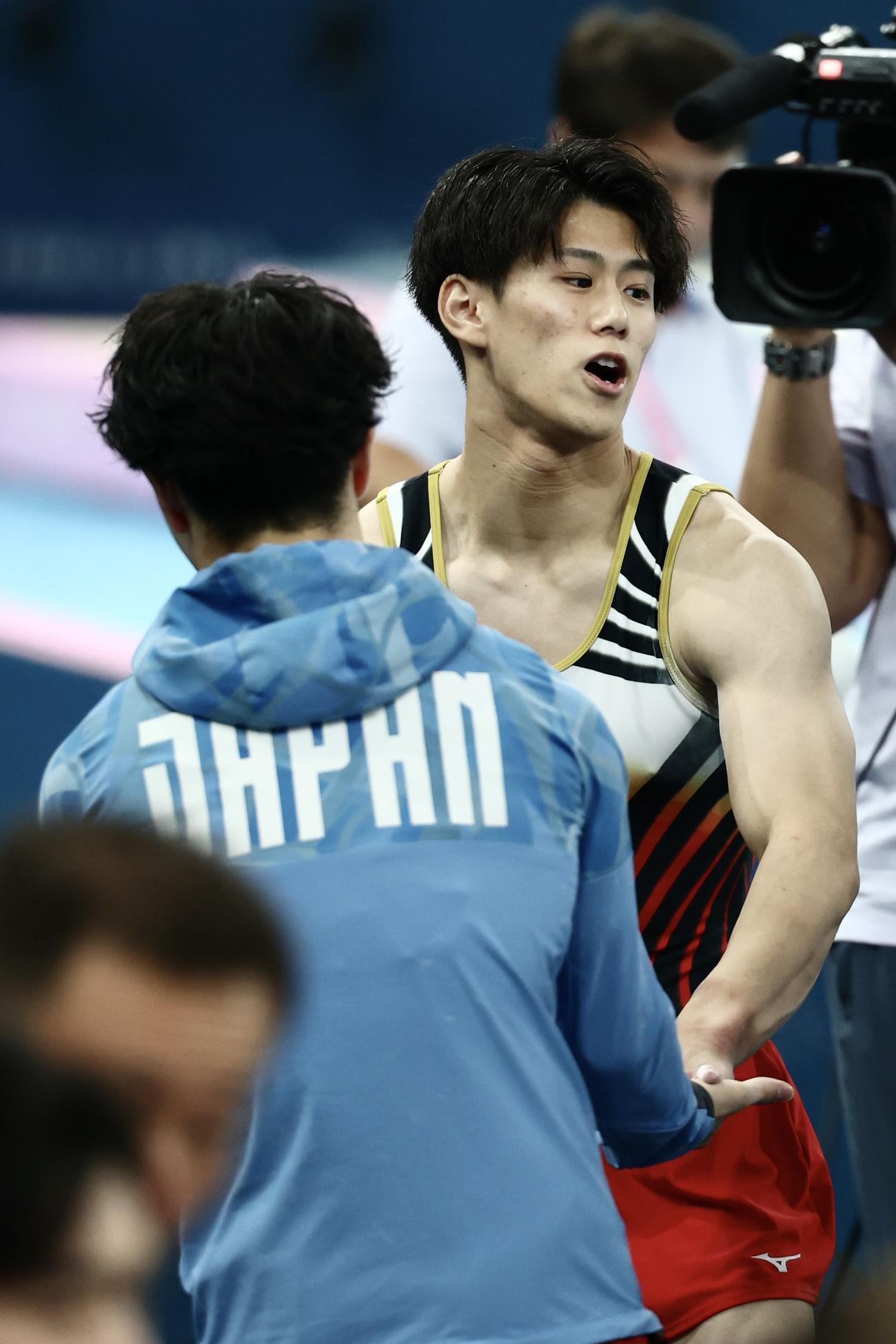 男子個人総合決勝　男子個人総合決勝　跳馬の演技を終え、岡（手前）とタッチを交わす橋本（撮影・河田真司）