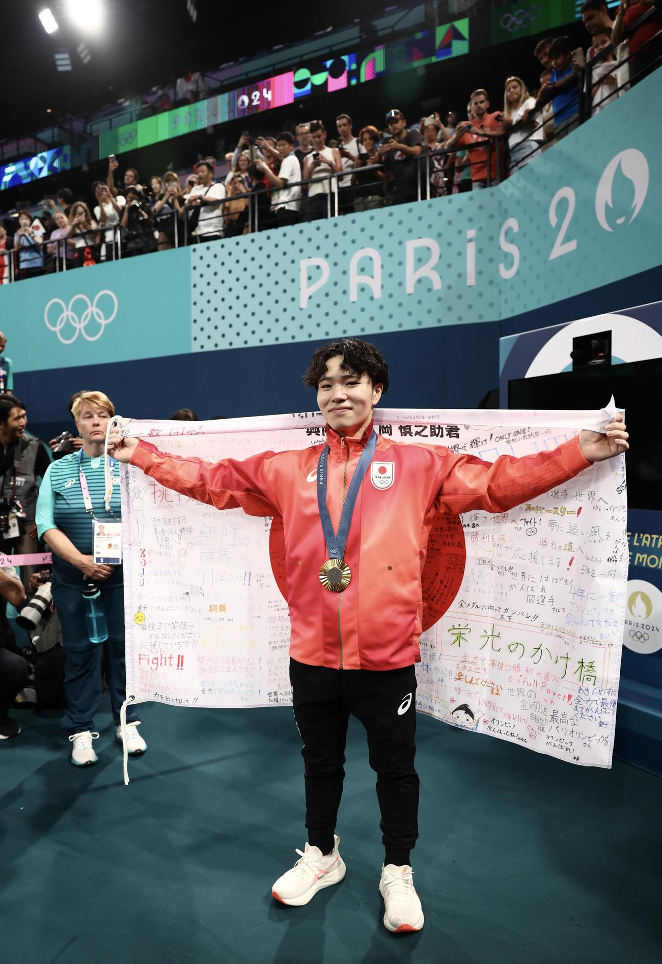 男子個人総合で金メダルを決め、日の丸を広げ記念撮影する岡（撮影・河田真司）