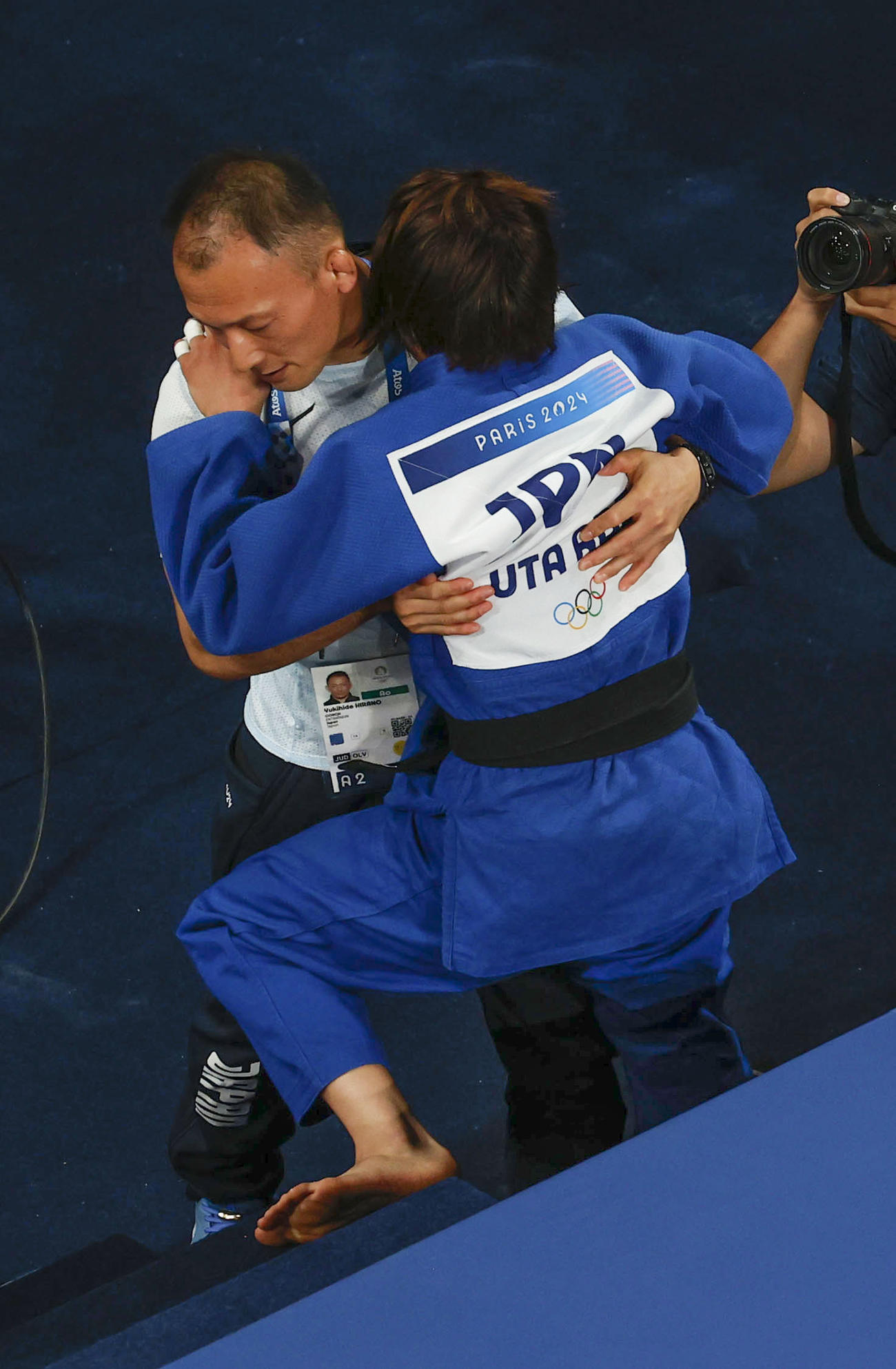 女子52キロ級2回戦で敗れ平野幸秀コーチ（左）に抱きかかえられる阿部詩（共同）
