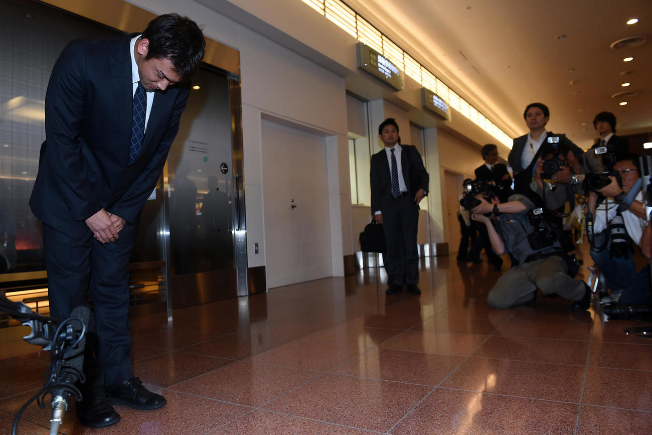 羽田空港に到着した競泳男子の冨田は、報道陣の前で深々と頭を下げる（2014年10月1日）