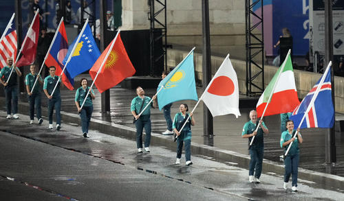パリ五輪の開会式で運ばれる日本などの国旗（共同）