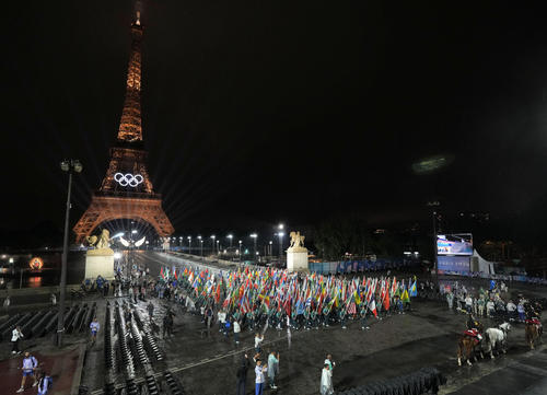 パリ五輪の開会式で集まった各国の国旗。奥はエッフェル塔（共同）