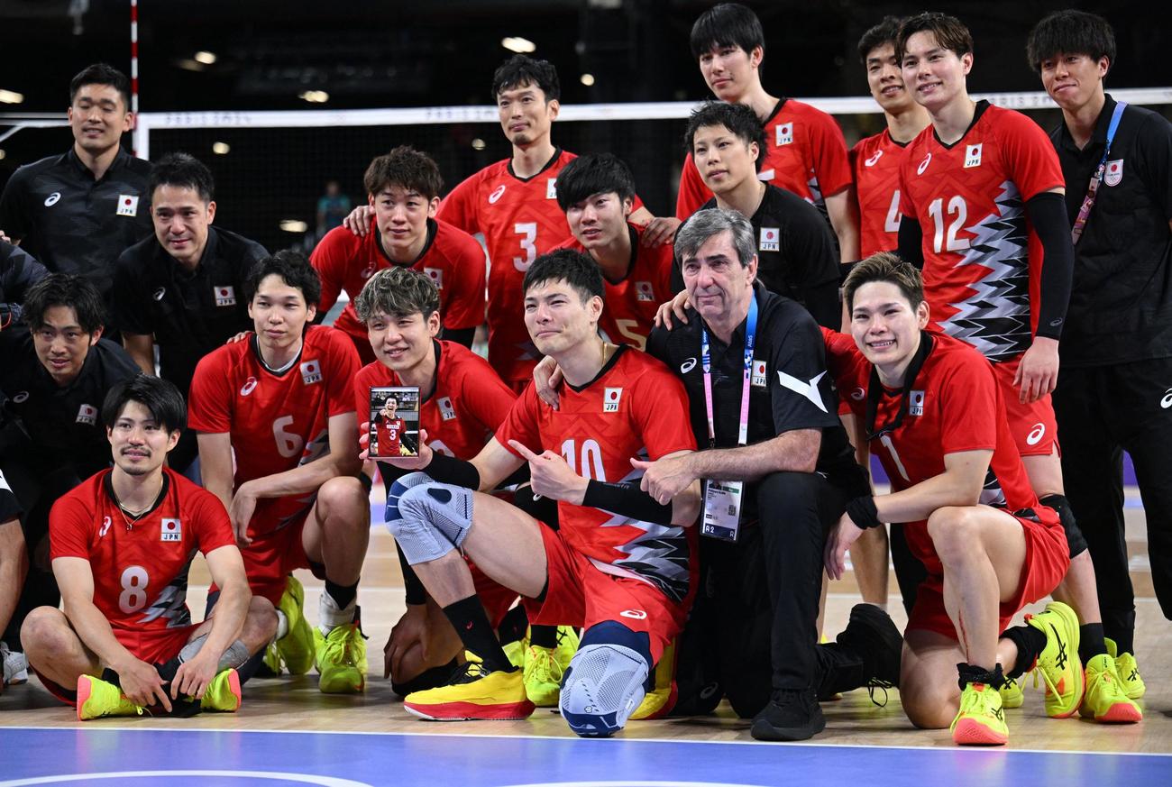 故藤井直伸さんの写真とともに、集合写真を撮る日本代表の選手たちと、ブラン監督（ロイター）
