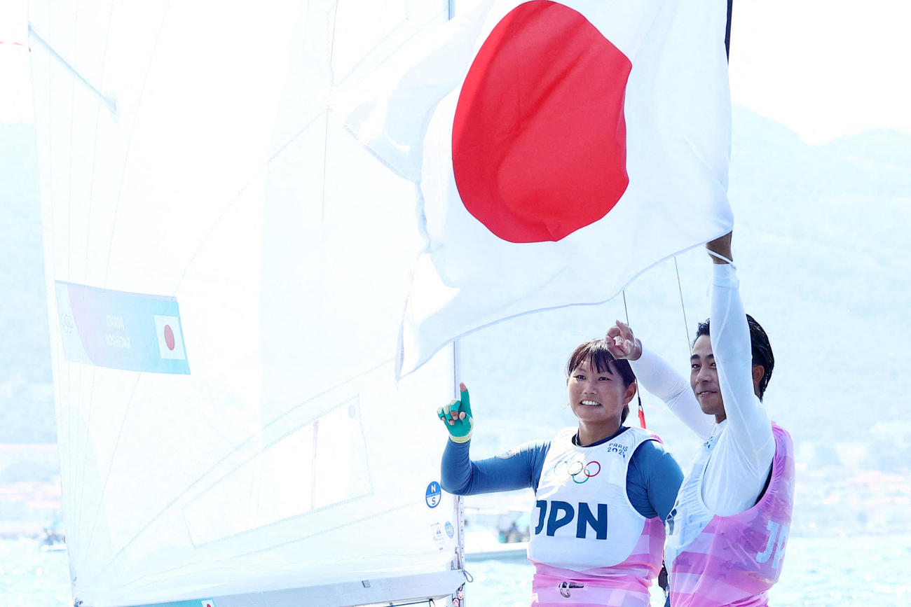 混合470級で銀メダルを獲得し、ヨットの上で日の丸を掲げる岡田奎樹、吉岡美帆組（ロイター)