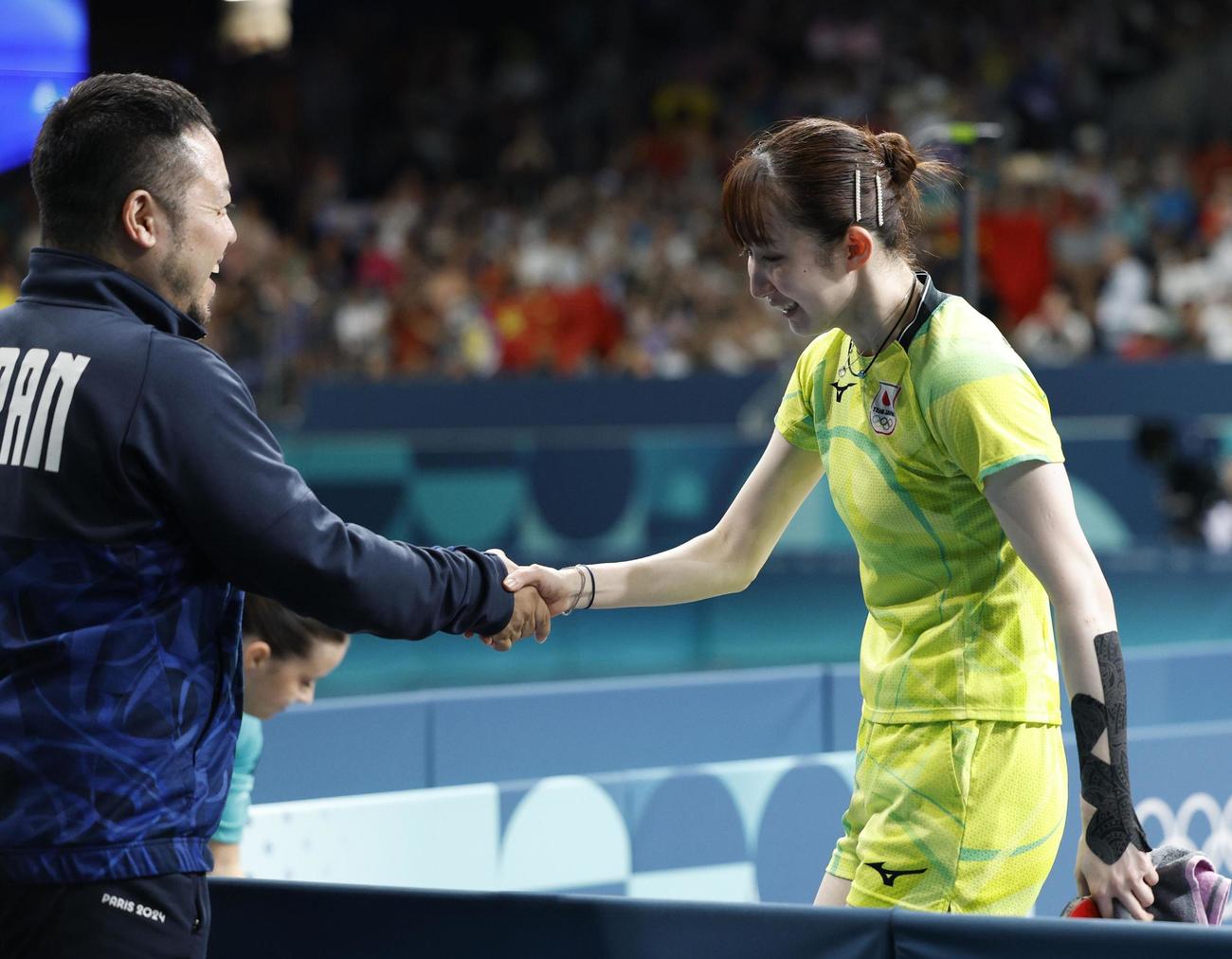 女子シングルス準決勝で敗れ、石田コーチ（左）と握手する早田ひな＝パリ（共同）