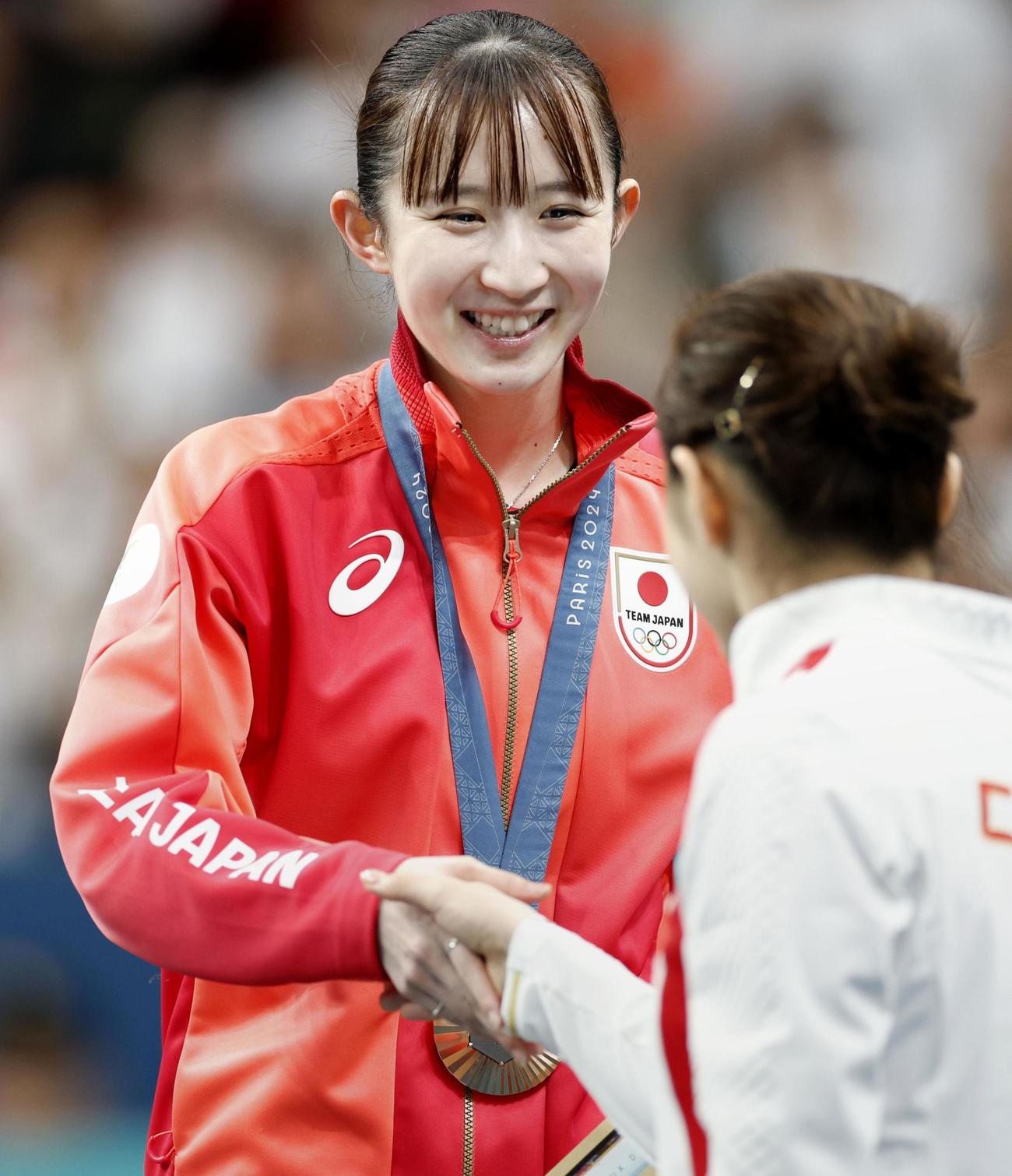 卓球女子シングルスで銅メダルを獲得し、優勝した中国の陳夢と握手する早田ひな（共同）