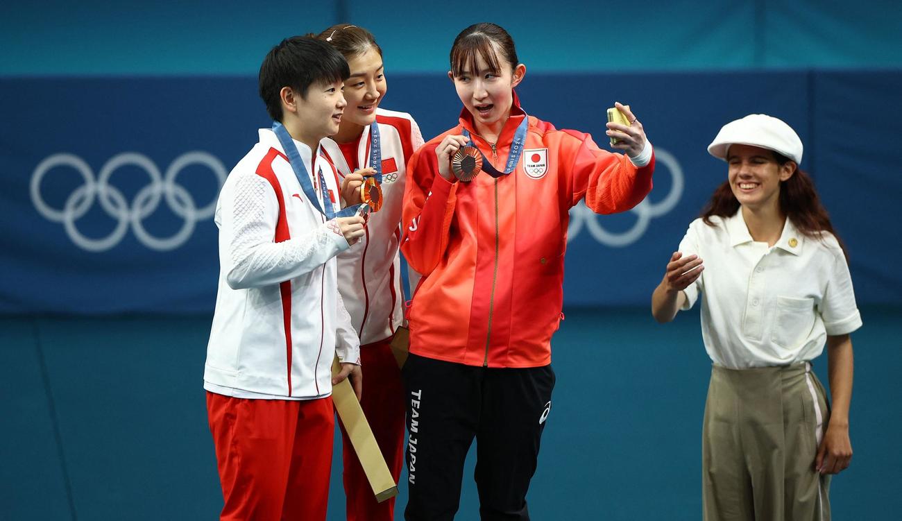 パリ五輪卓球女子シングルスの表彰台で銀メダリストの孫穎莎（左端）、金メダリストの陳夢（左から2人目）と自撮りする銅メダリストの早田ひな（中央）（ロイター）