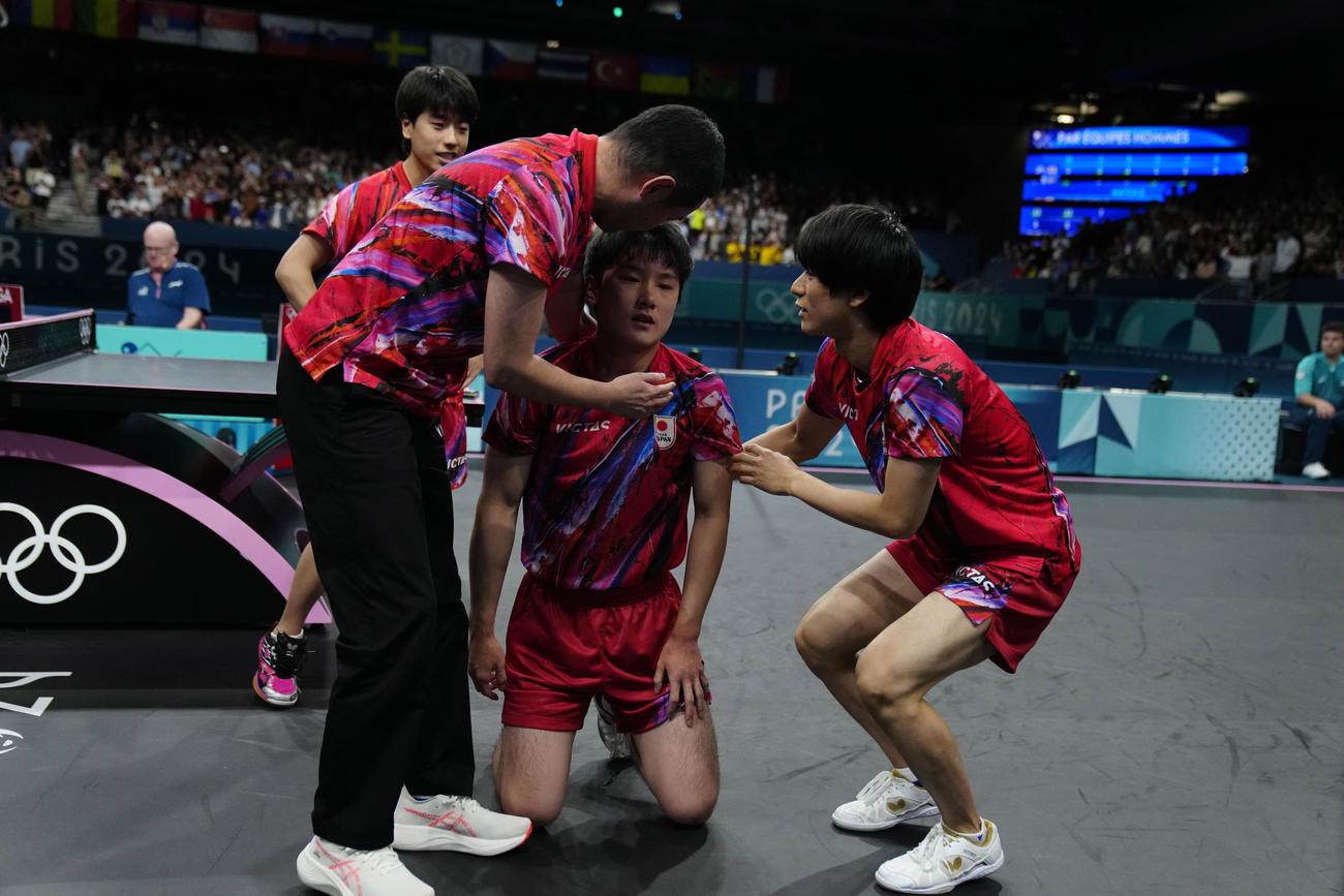 卓球男子団体準決勝　日本対スウェーデン　フルセットの末、敗れ落胆する張本（中央）を支えるチームメート (AP)
