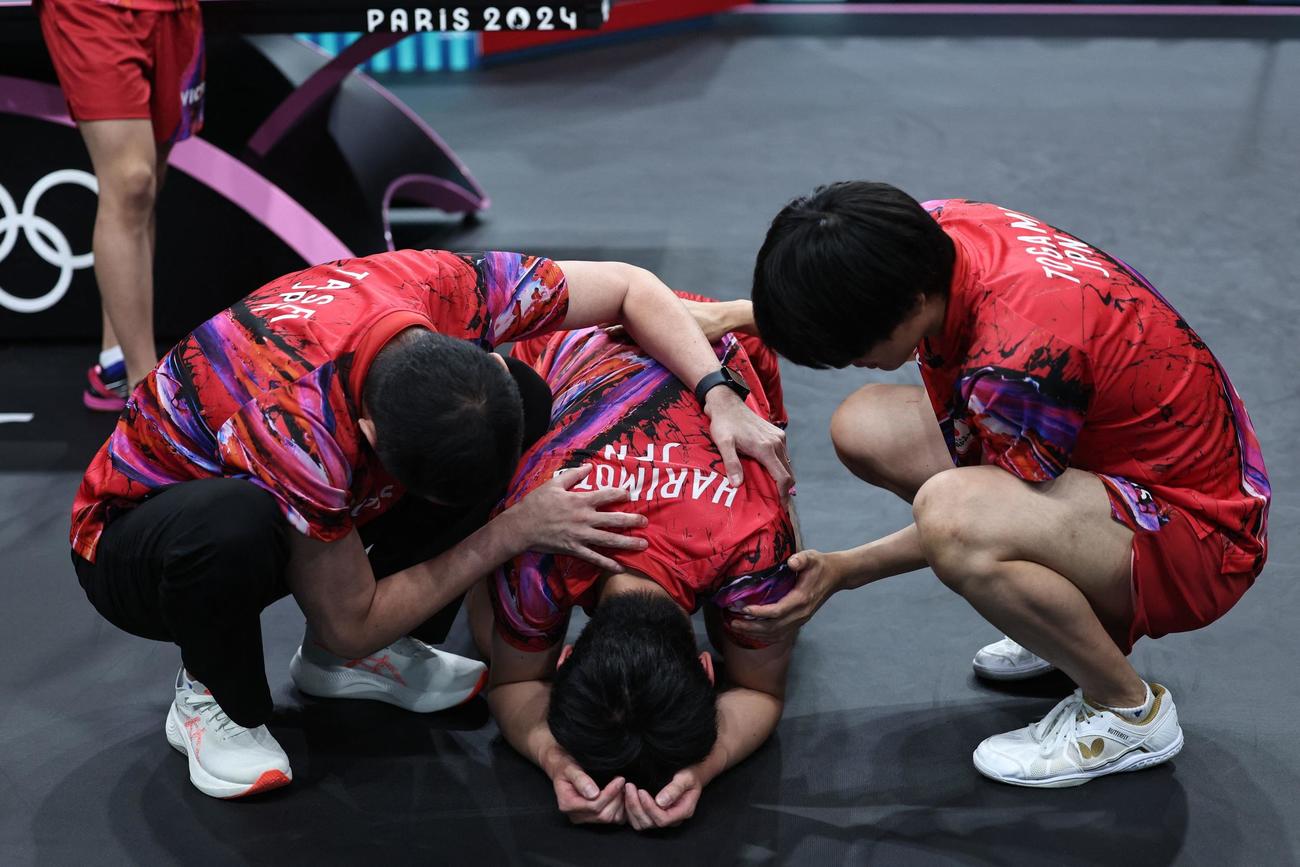 卓球男子団体準決勝　日本対スウェーデン　フルセットの末、敗れひざから崩れ落ちる張本を支えるチームメート(ロイター)